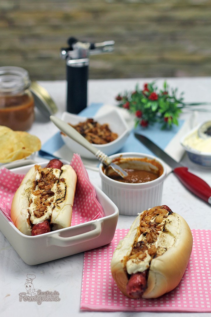 Sanduíche estilo food truck feito com linguiça defumada, molho barbecue de tomate pelado, cream cheese maçaricado no pão de cachorro-quente com cebola crocante (crispy).