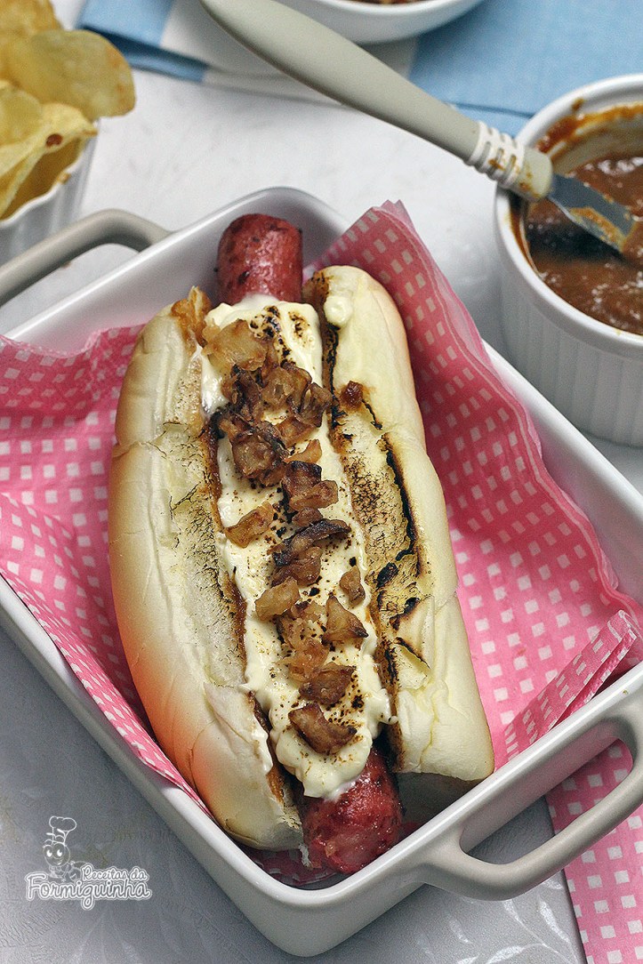 Sanduíche estilo food truck feito com linguiça defumada, molho barbecue de tomate pelado, cream cheese maçaricado no pão de cachorro-quente com cebola crocante (crispy).